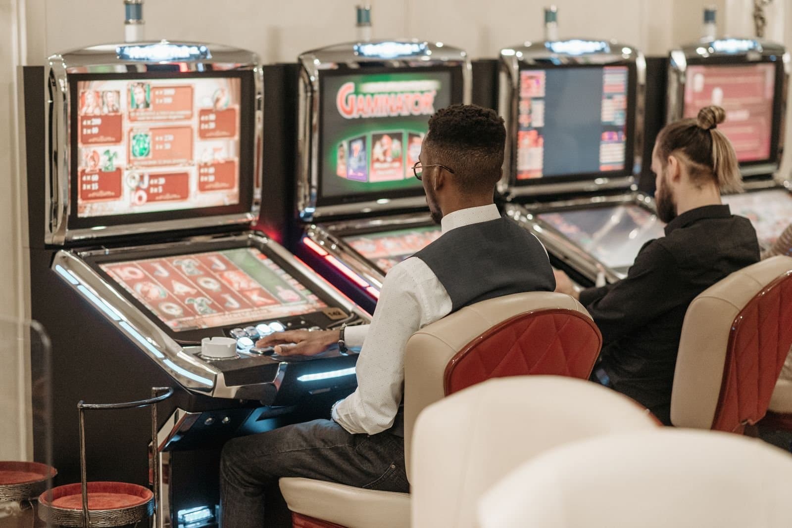 Two players seated at slot machines in a casino