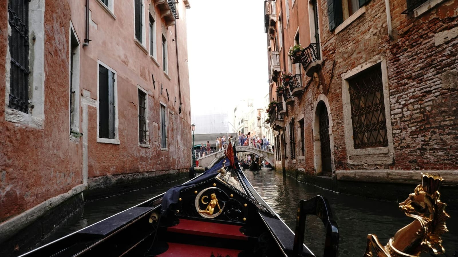 A gondola in a narrow canal between Venetian buildings.