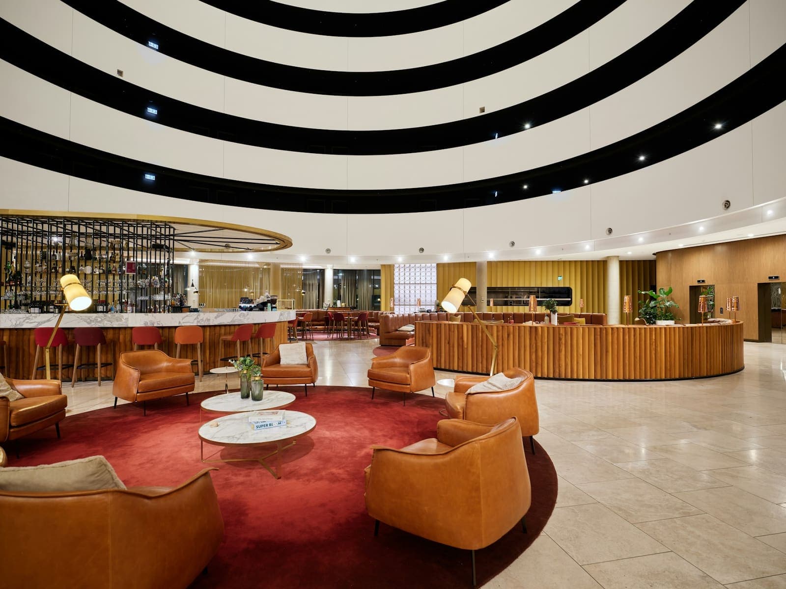 A modern hotel lobby with circular seating and a bar in the background.